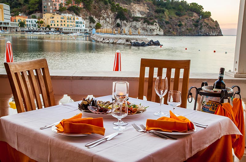 Tavolo apparecchiato in terrazza con vista sul mare